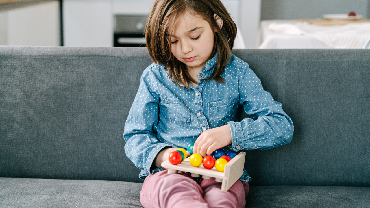 A Girl Sitting On Couch While Playing A Toy